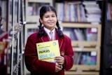 A student holding a book near the library shelves